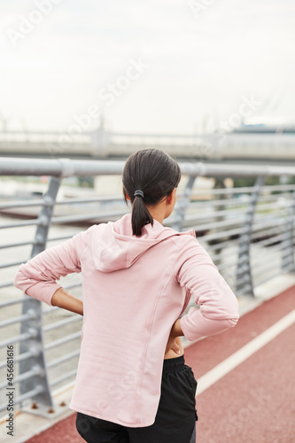 Rear view of young woman standing on sport stadium and training alone outdoors