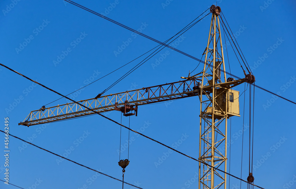 Yellow crane on a background of blue sky. Yellow crane at the construction site. Yellow crane on a background of blue sky. Yellow crane at the construction site.