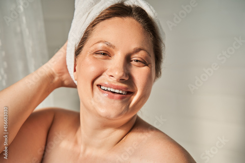 Woman with towel at her head laughing and looking at the camera while feeling glad