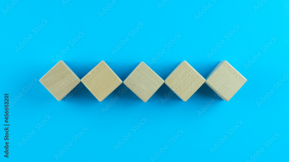 Pyramid of five wooden cubes, on blue background