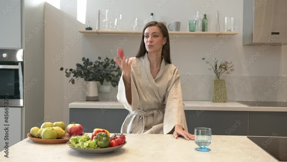 Food blogger, smiling and attractive woman standing on background of kitchen room, table with plates of fresh fruits and vegetables. Vegan lifestyle and diet, gimbal shot Food blogger, smiling and attractive woman standing on background of kitchen room, table with plates of fresh fruits and vegetables. Vegan lifestyle and diet, gimbal shot