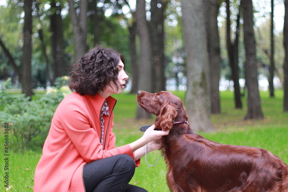 Beautiful young woman and red Irish setter in the park