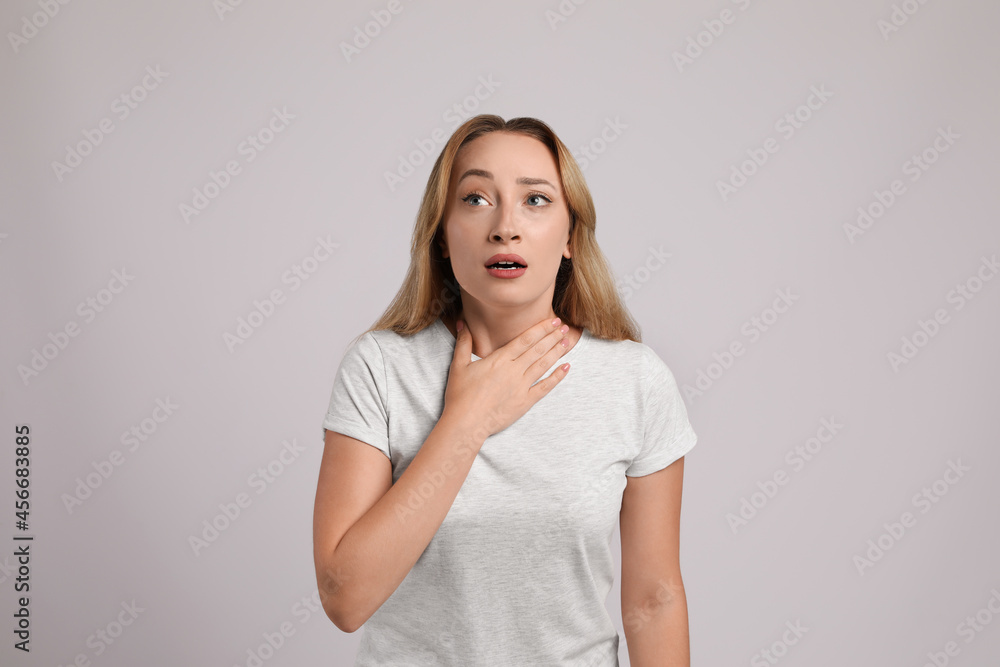 Young woman suffering from pain during breathing on light grey background Young woman suffering from pain during breathing on light grey background