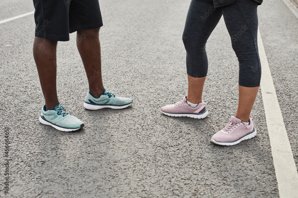 Close-up of young couple in sports shoes meeting outdoors to train together
