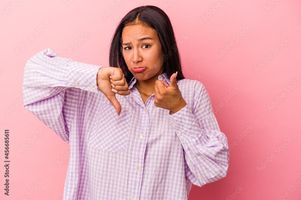 Young latin woman isolated on pink background showing thumbs up and thumbs down, difficult choose concept Young latin woman isolated on pink background showing thumbs up and thumbs down, difficult choose concept