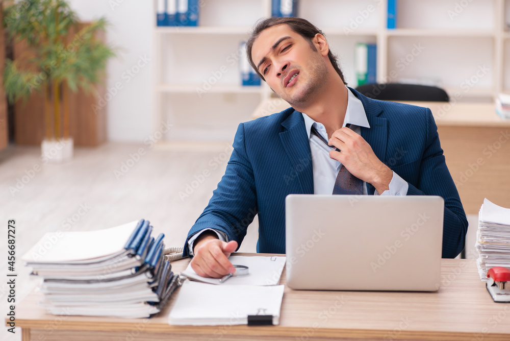 Fototapeta premium Young male employee unhappy with excessive work