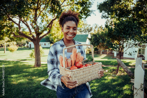 Mixed race female walking through farm village smiling looking happy after picking fresh vegetables from garden  © Prins Productions
