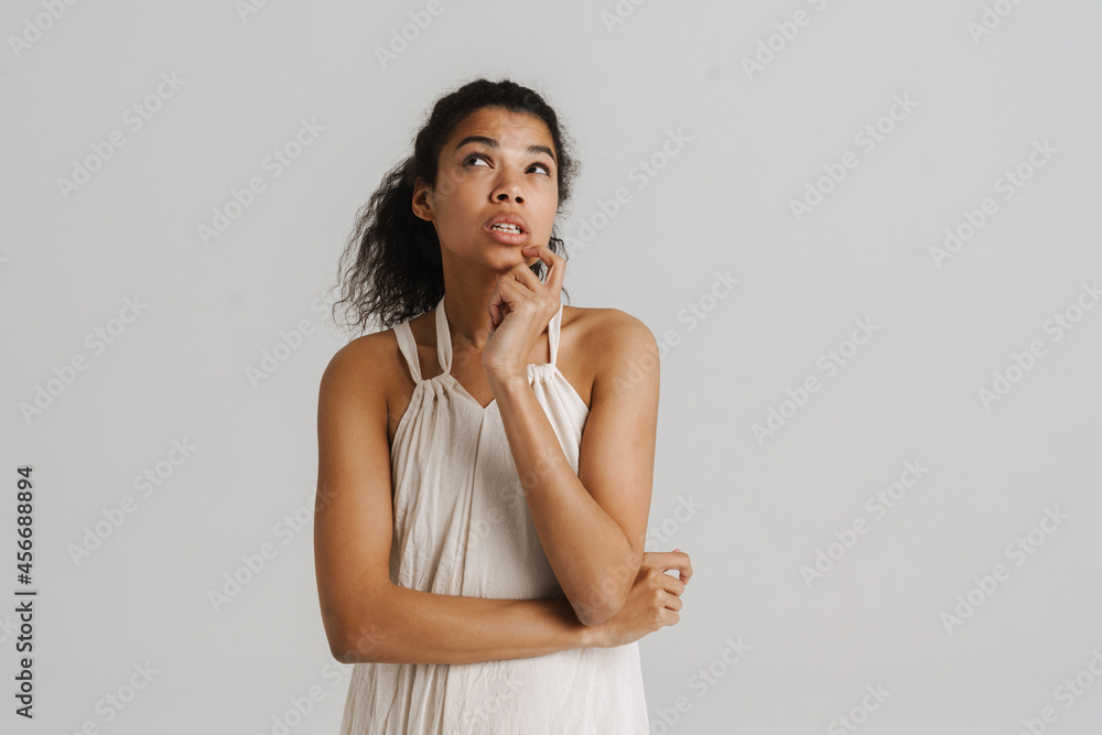 Black young woman in dress thinking and looking upward Black young woman in dress thinking and looking upward