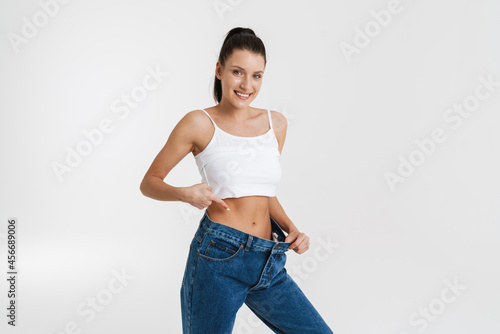 European woman pointing finger at her waist while posing in big jeans © Drobot Dean