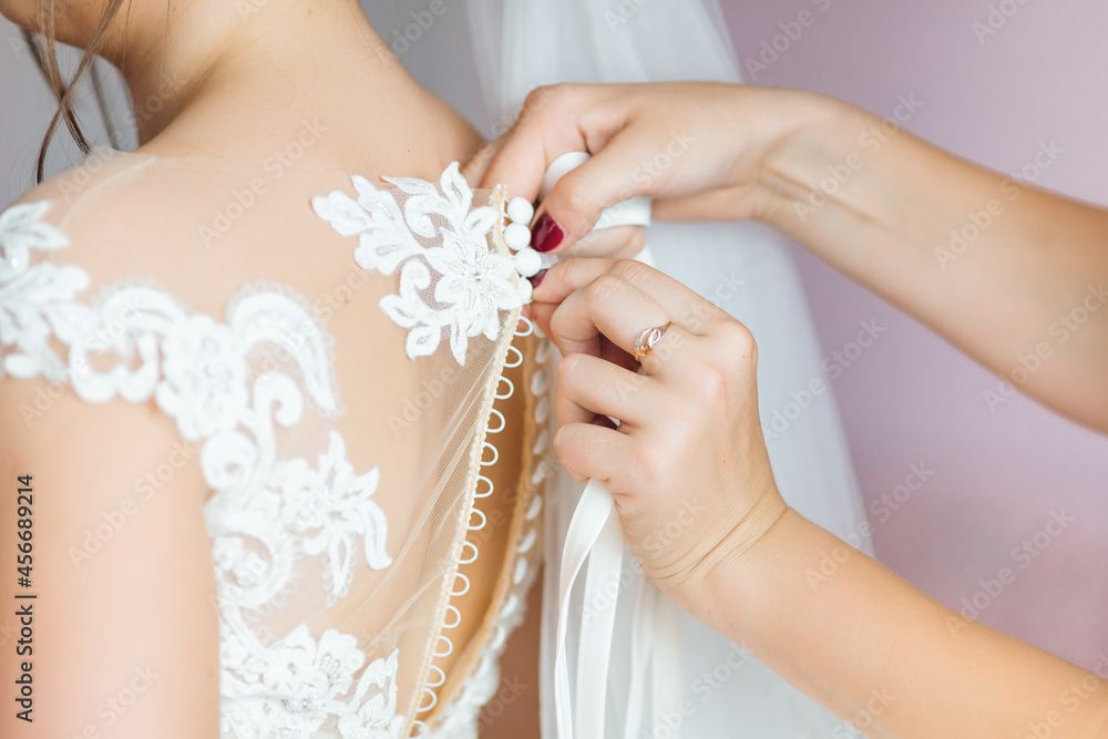 The bridesmaids help to secure the bride's wedding dress before the ceremony. Luxurious wedding dress. Best morning The bridesmaids help to secure the bride's wedding dress before the ceremony. Luxurious wedding dress. Best morning