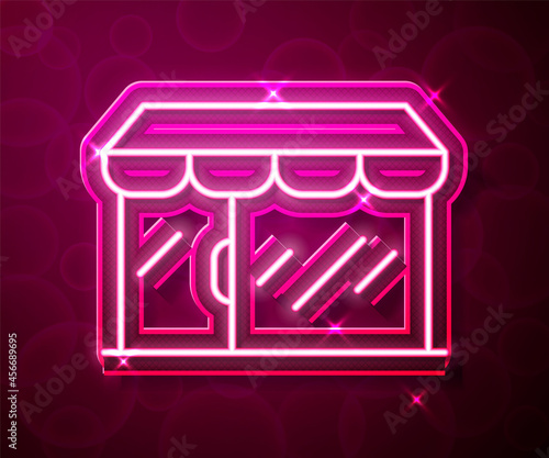 Glowing neon line Shopping building or market store icon isolated on red background. Shop construction. Vector