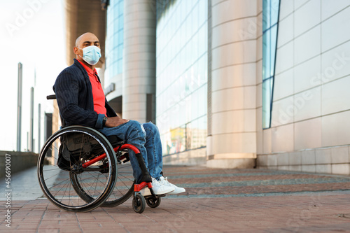 Man wearing face mask looking at camera while sitting in wheelchair © Drobot Dean