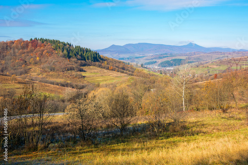 countryside mountain landscape in autumn. trees in colorful foliage on hills rolling in to the distant ridge. beautiful sunny morning in carpathians