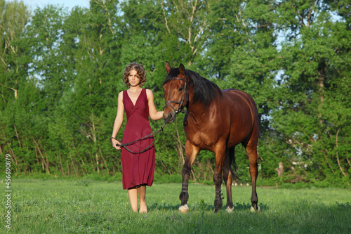 Beautiful lady bareback lead her horse in woods glade at sunset © horsemen