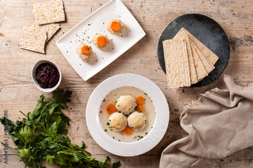 Traditional Jewish matzah ball soup, gefilte fish and matzah bread on wooden table	