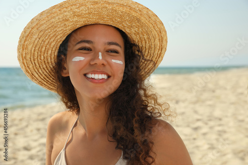 Beautiful African American woman with sun protection cream on face at beach