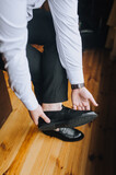 A man businessman in a white shirt puts on black shiny shoes, going to work in the morning.