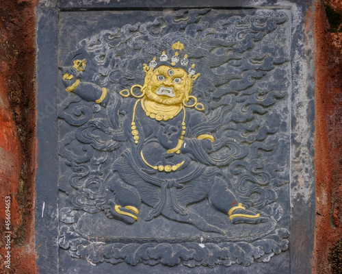 Beautiful gold plated carved votive slate representing Mahakala on a chorten or stupa at Dochula pass, Bhutan photo