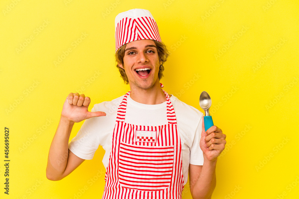 Young ice cream maker man with makeup holding spoon isolated on yellow background person pointing by hand to a shirt copy space, proud and confident Young ice cream maker man with makeup holding spoon isolated on yellow background person pointing by hand to a shirt copy space, proud and confident