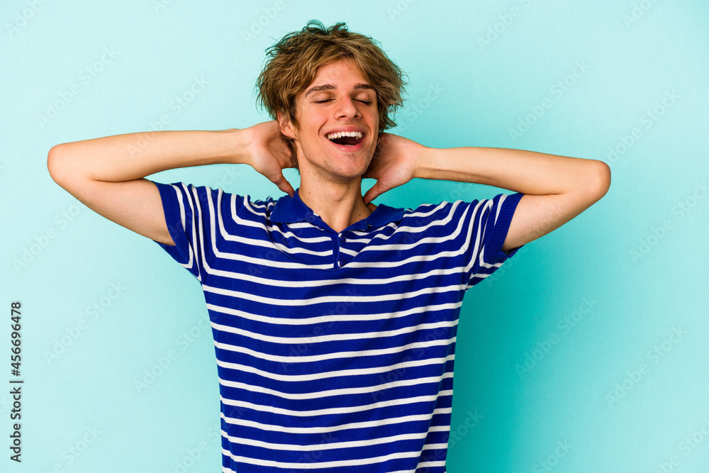 Young caucasian man with make up isolated on blue background feeling confident, with hands behind the head. Young caucasian man with make up isolated on blue background feeling confident, with hands behind the head.