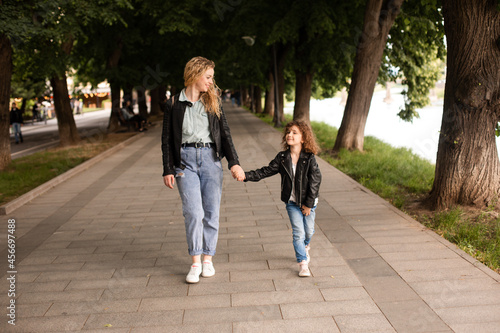 The mom and little girl walk together along the waterfront