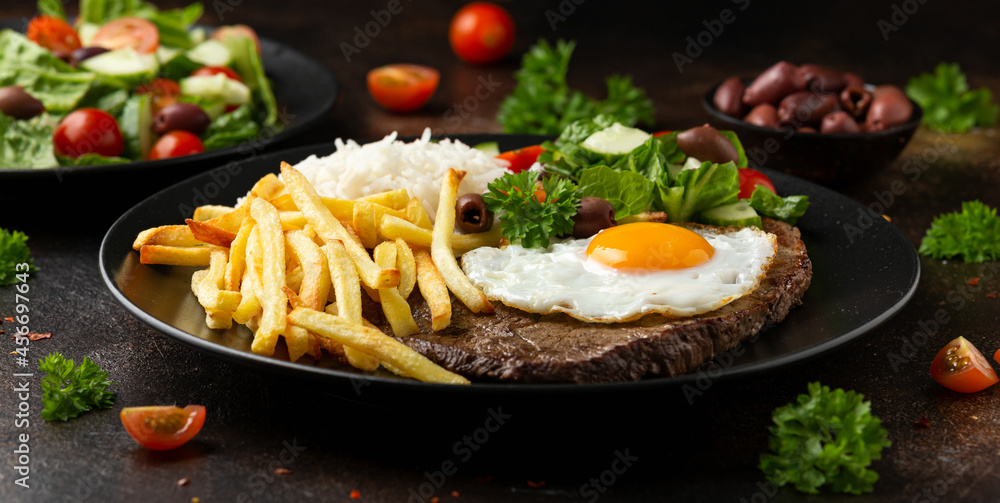 Portugal dish Bitoque made from beef steak with a fried egg, rice, french fries and vegetables - obrazy, fototapety, plakaty 