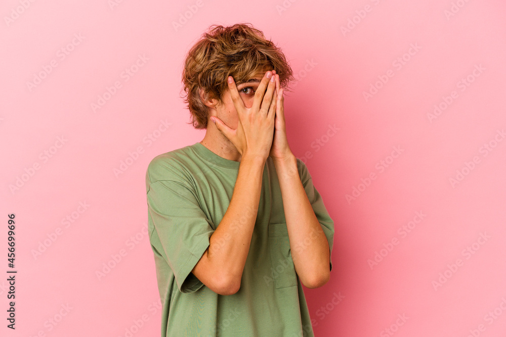 Young caucasian man with make up isolated on pink background blink through fingers frightened and nervous. Young caucasian man with make up isolated on pink background blink through fingers frightened and nervous.
