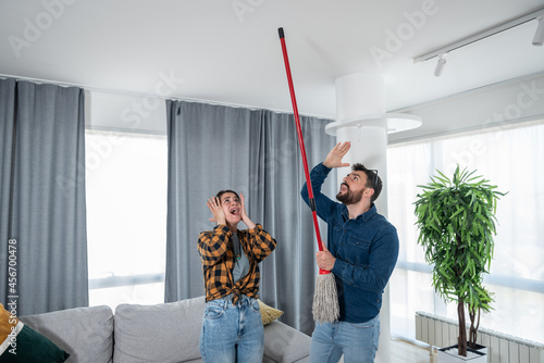 Young couple stares at the ceiling and yells because a neighbor upstairs is having a party with loud music or renovating an apartment and workers are drilling with heavy tools
