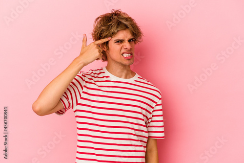Young caucasian man with make up isolated on pink background covering ears with hands.