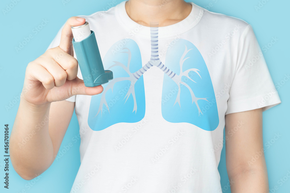 Fototapeta premium Young woman using blue asthma inhaler for relief asthma attack. Pharmaceutical products is used to prevent and treat wheezing and shortness of breath caused asthma or COPD. Lung organ anatomy.
