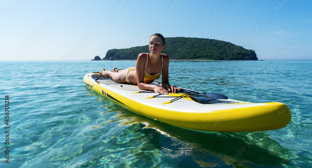 Relaxed travel woman in swimsuit sunbathing on surfboard enjoying sup surfing extreme sport