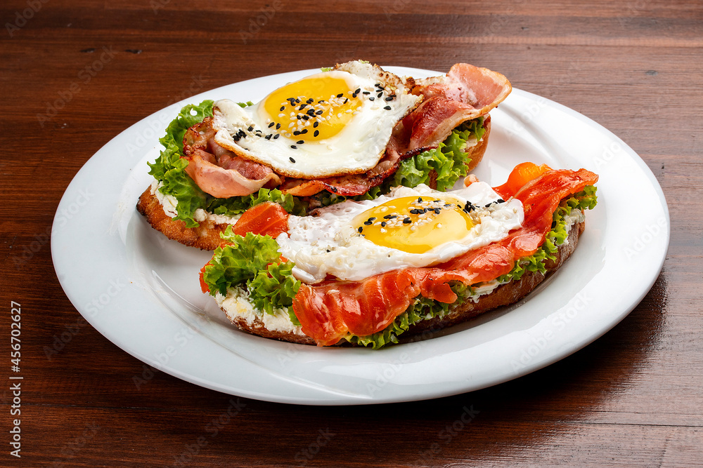 Toast with salmon, bacon and cream cheese.  On a wooden background. Breakfast