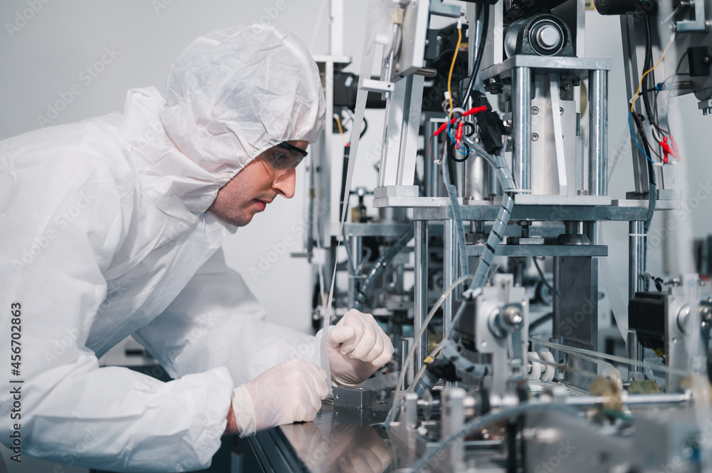 Scientists wearing protective clothing Inspect mask making machines in a laboratory at an industrial plant. Anti-virus production warehouse. concept of safety and prevention coronavirus covid-19. Scientists wearing protective clothing Inspect mask making machines in a laboratory at an industrial plant. Anti-virus production warehouse. concept of safety and prevention coronavirus covid-19.