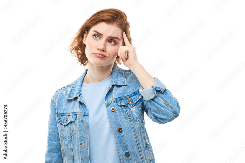 Portrait of young attractive beautiful thoughtful happy redhead female student thinking looking at copyspace, isolated on white background. Woman in blue jeans