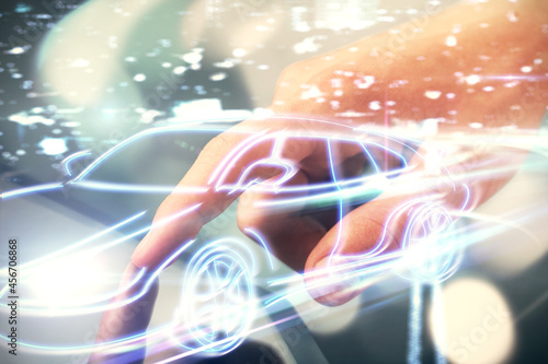 Double exposure of man's hands holding and using a digital device and automobile theme hologram drawing. Technology concept.