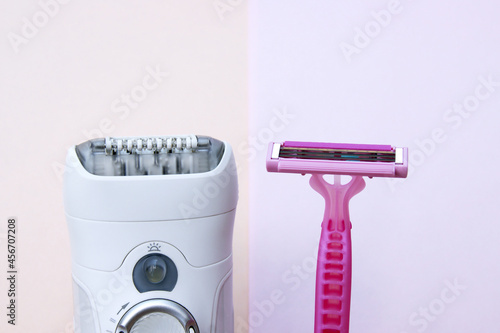 White epilator and pink razor on a pink background.