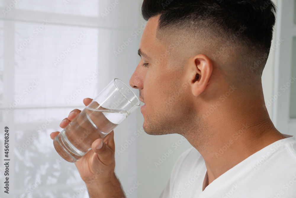 Man drinking tap water from glass at home, closeup Man drinking tap water from glass at home, closeup