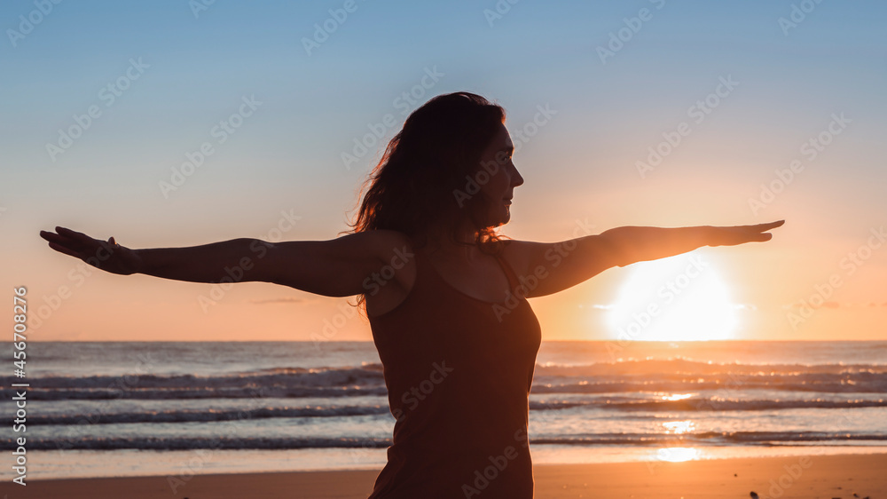 Silhouette of woman on the beach in yoga position