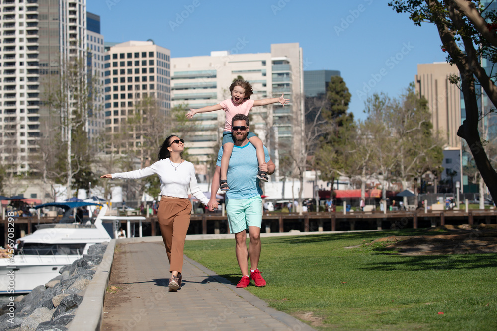 Portrait of happy young family holding hands walking with their child on the city. People urban concept.