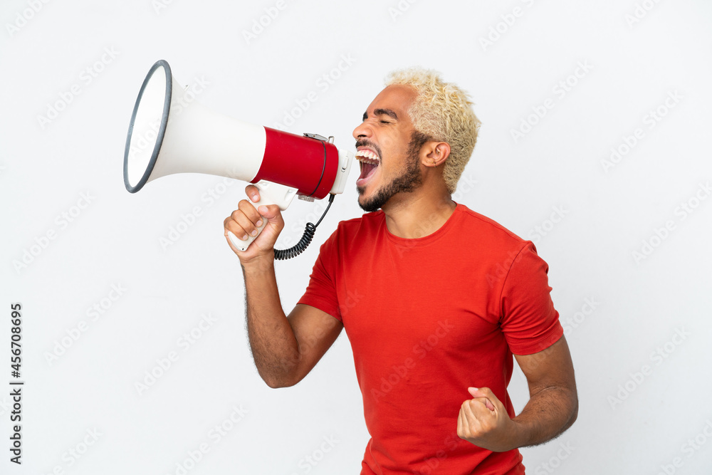 Young Colombian handsome man isolated on white background shouting through a megaphone to announce something in lateral position Young Colombian handsome man isolated on white background shouting through a megaphone to announce something in lateral position