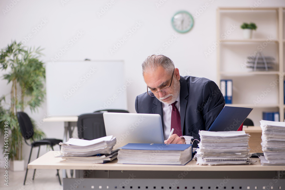 Aged male employee and too much work at workplace Aged male employee and too much work at workplace