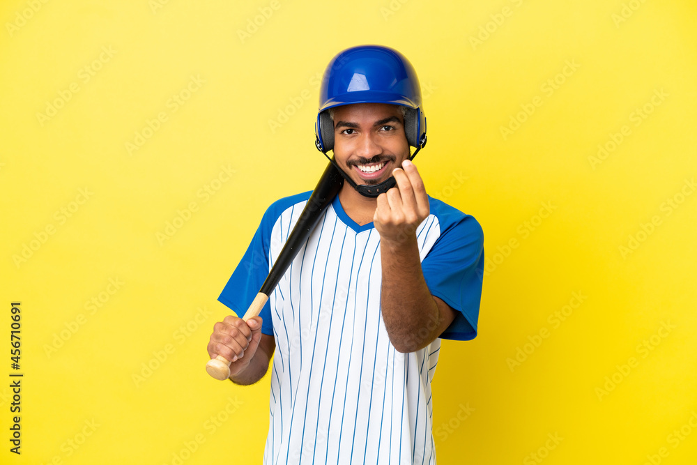 Young Colombian latin man playing baseball isolated on yellow background making money gesture