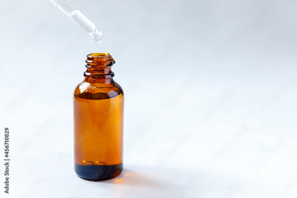 Essential oil dropping from pipette to bottle. Essence liquid cosmetic. Dropper glass bottle with liquid cosmetic serum. Syrup, perfume, aromatherapy concept. Beauty Treatment Essential oil dropping from pipette to bottle. Essence liquid cosmetic. Dropper glass bottle with liquid cosmetic serum. Syrup, perfume, aromatherapy concept. Beauty Treatment