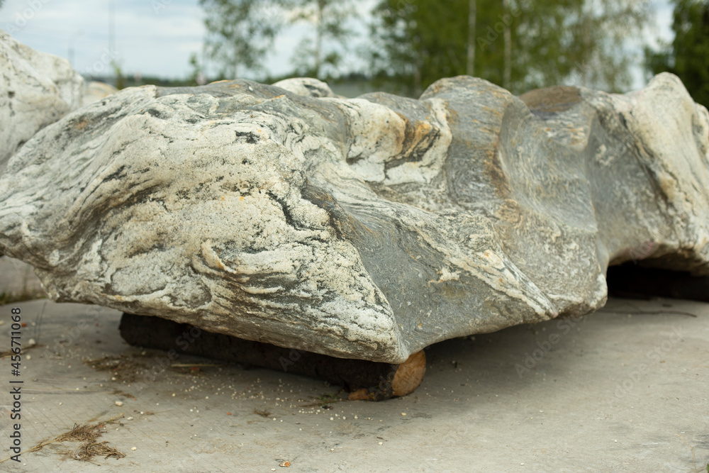 Fototapeta premium A large stone is installed in the park. Preparation of the rock for landscape design.