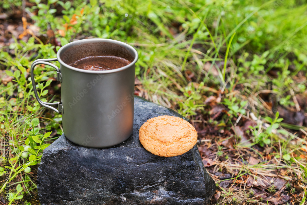 Warm cup of coffe with cookie on a stone - wild camping breakfast concept Warm cup of coffe with cookie on a stone - wild camping breakfast concept