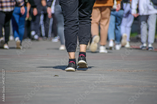 A man in sneakers walks along the sidewalk after a group of people