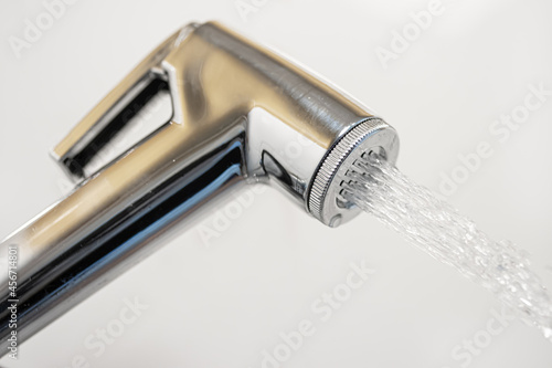 A chrome bidet shower spraying water, close up. photo