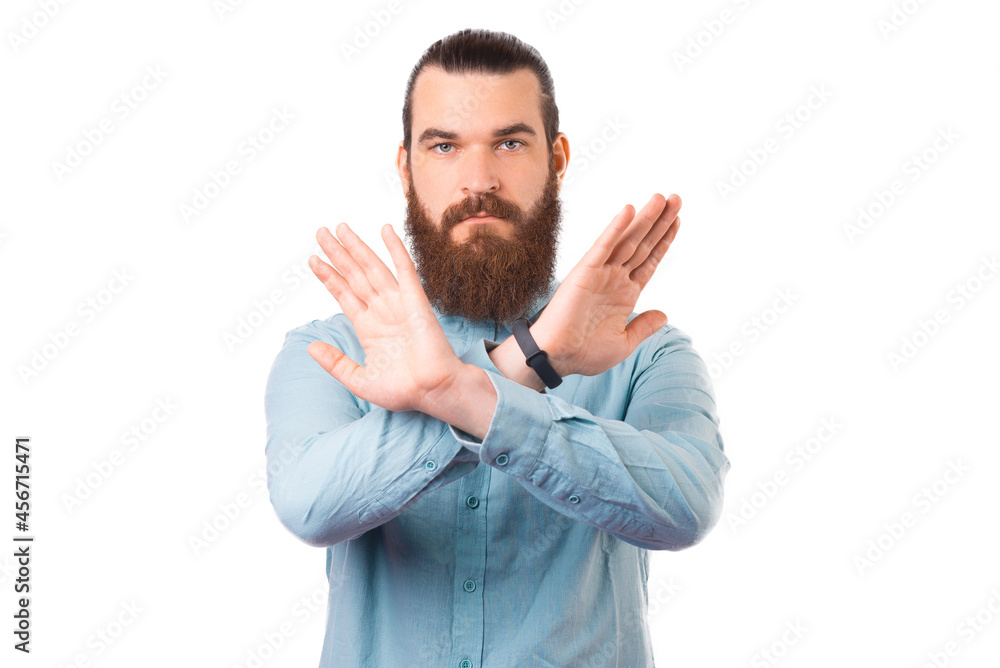 Young serious bearded man is making the prohibited sign over white background. Young serious bearded man is making the prohibited sign over white background.