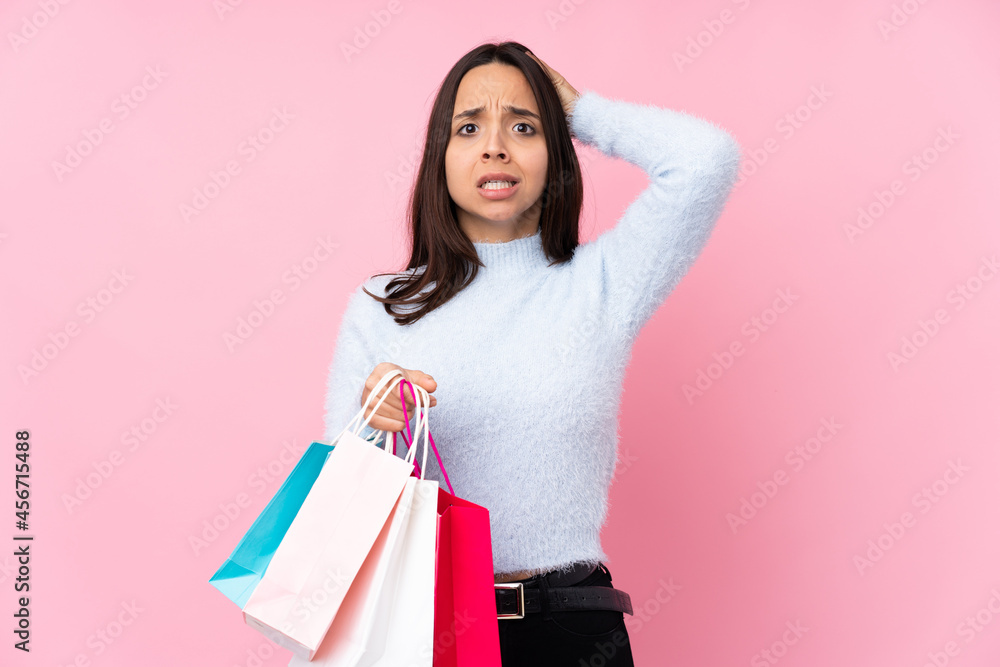 Young woman with shopping bag over isolated pink background frustrated and takes hands on head Young woman with shopping bag over isolated pink background frustrated and takes hands on head