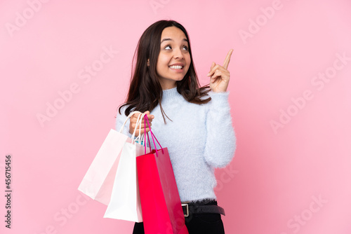 Young woman with shopping bag over isolated pink background pointing with the index finger a great idea